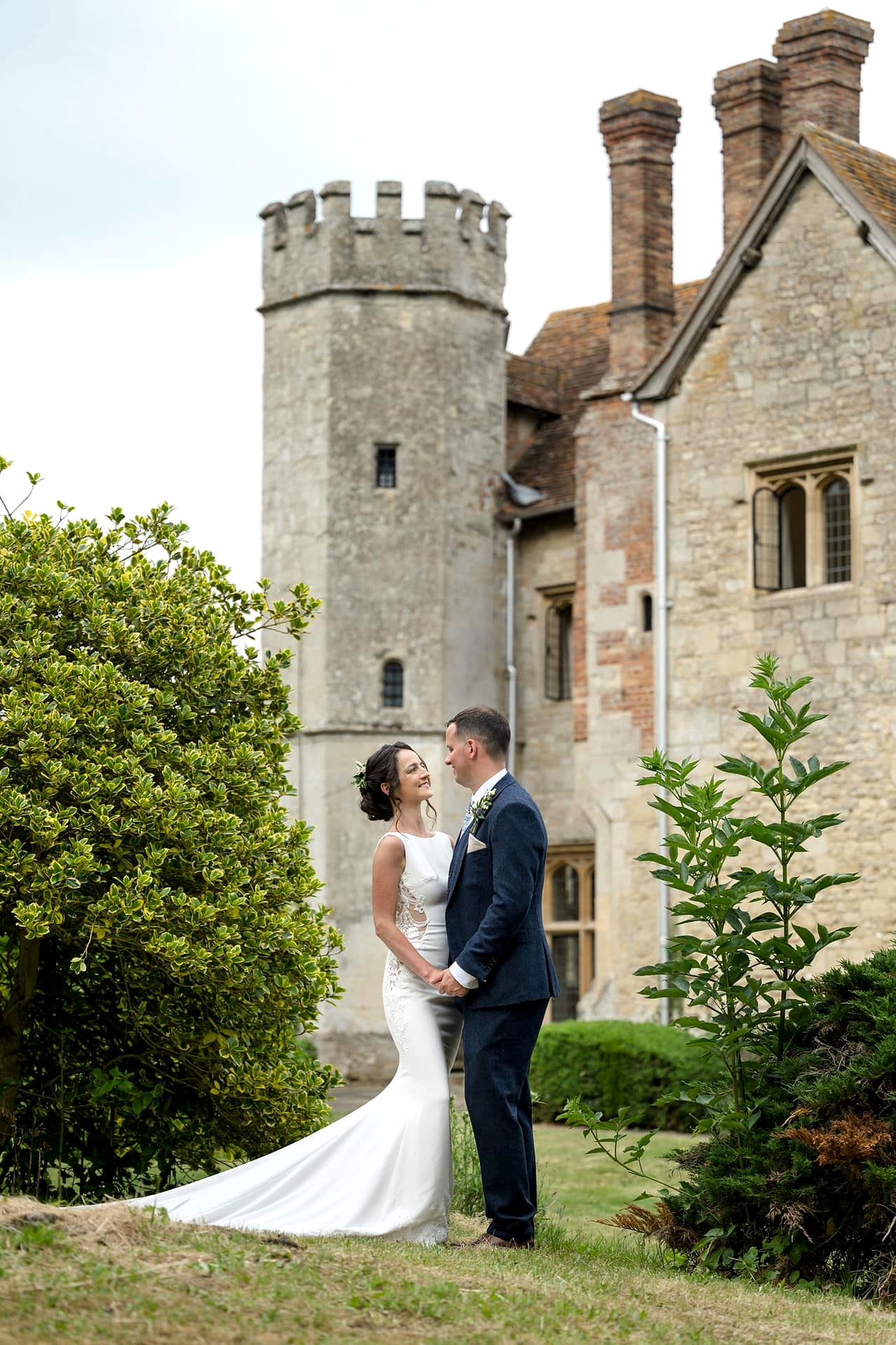 The bride and groom in front of a tower with turrets at Notley Abbey