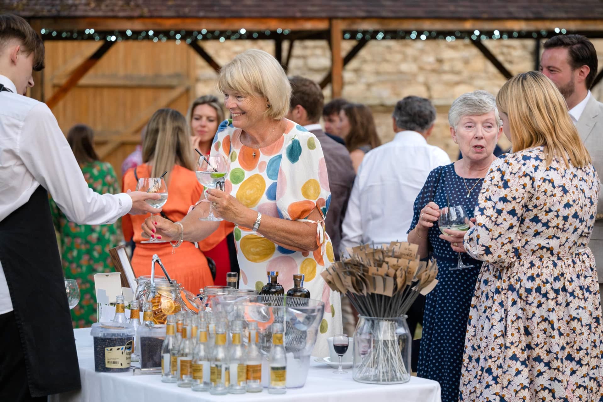 Wedding guests being served drinks from a gin bar outside at Notley Abbey