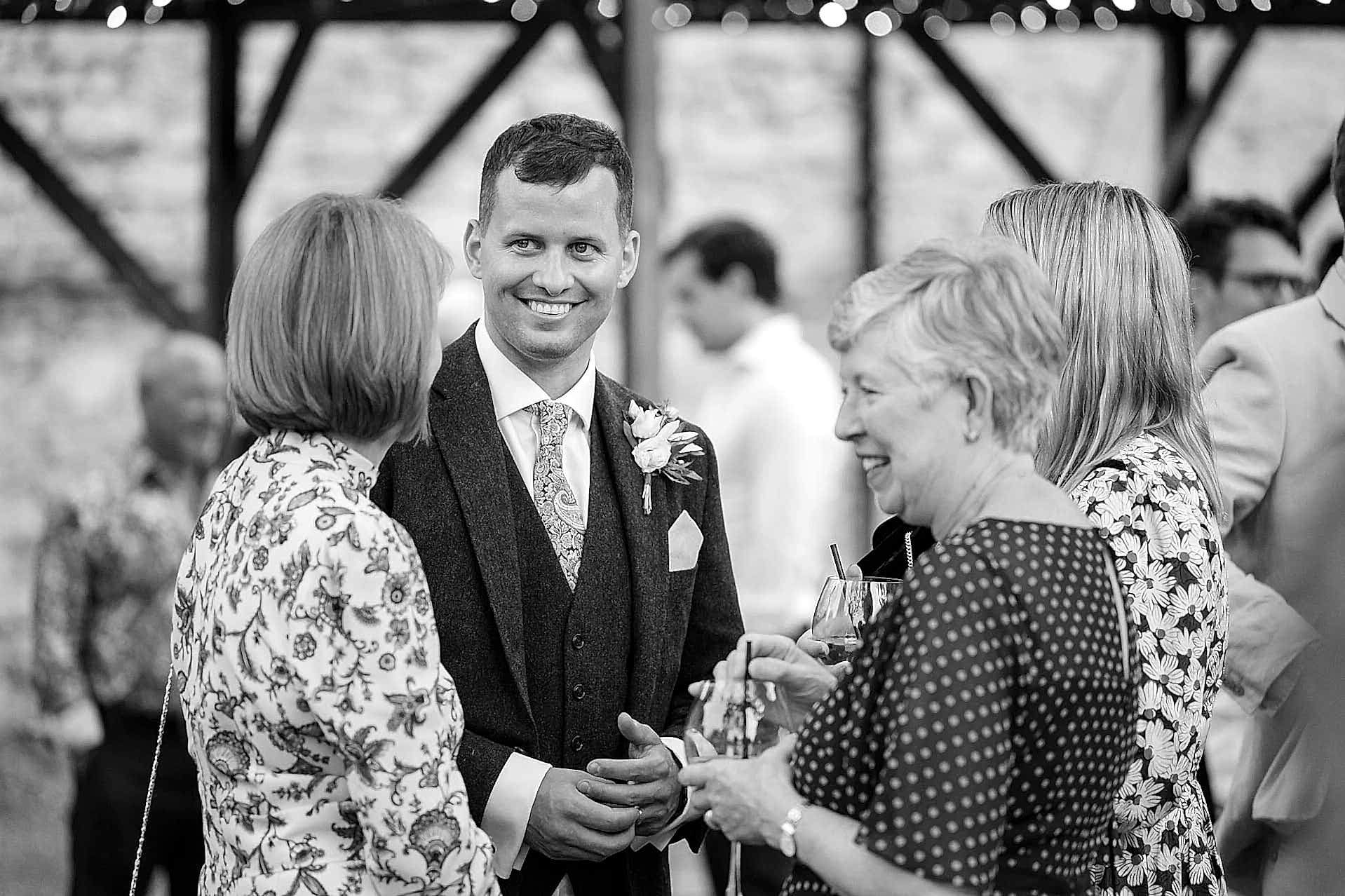 Groom fiddling with his wedding ring while chatting to wedding guests