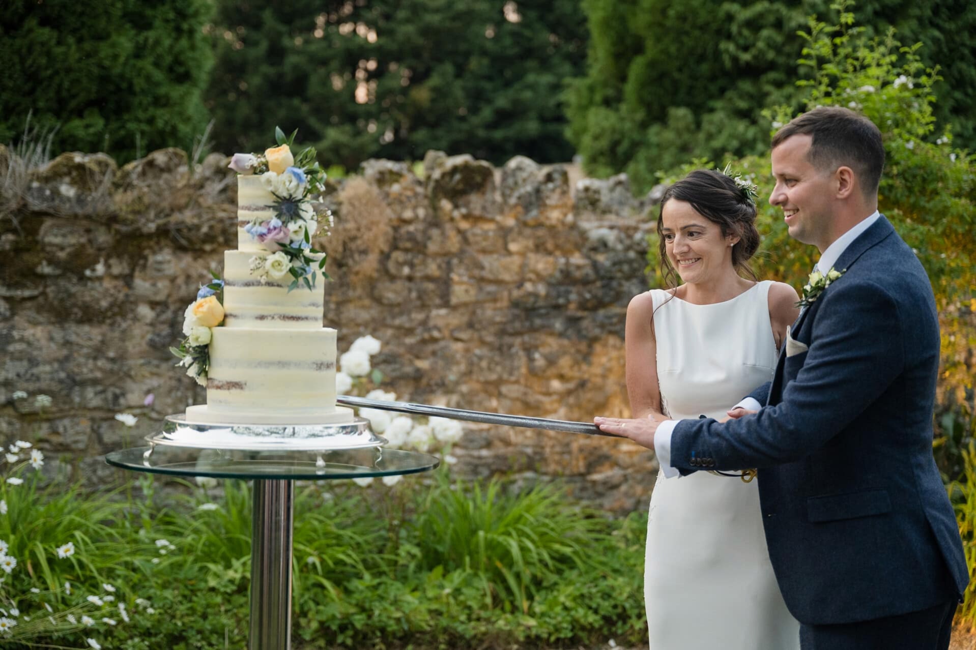 Bride and groom cutting their wedding cake with a sword