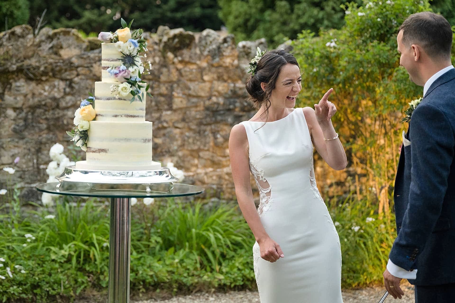 Bride pointing at the groom and laughing after he licked icing off the sword from cutting the cake