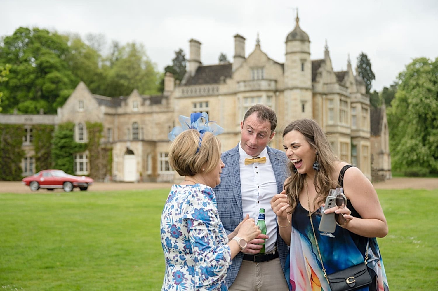 Three wedding guests giggling in front of Exton Park Hall