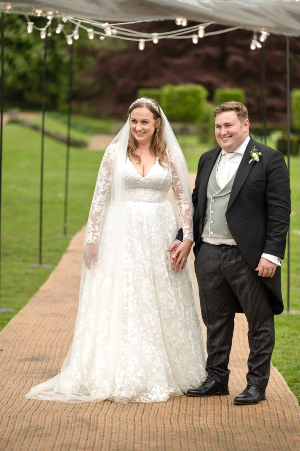Bride and groom holding hands as they wait to be announced into marquee for dinner