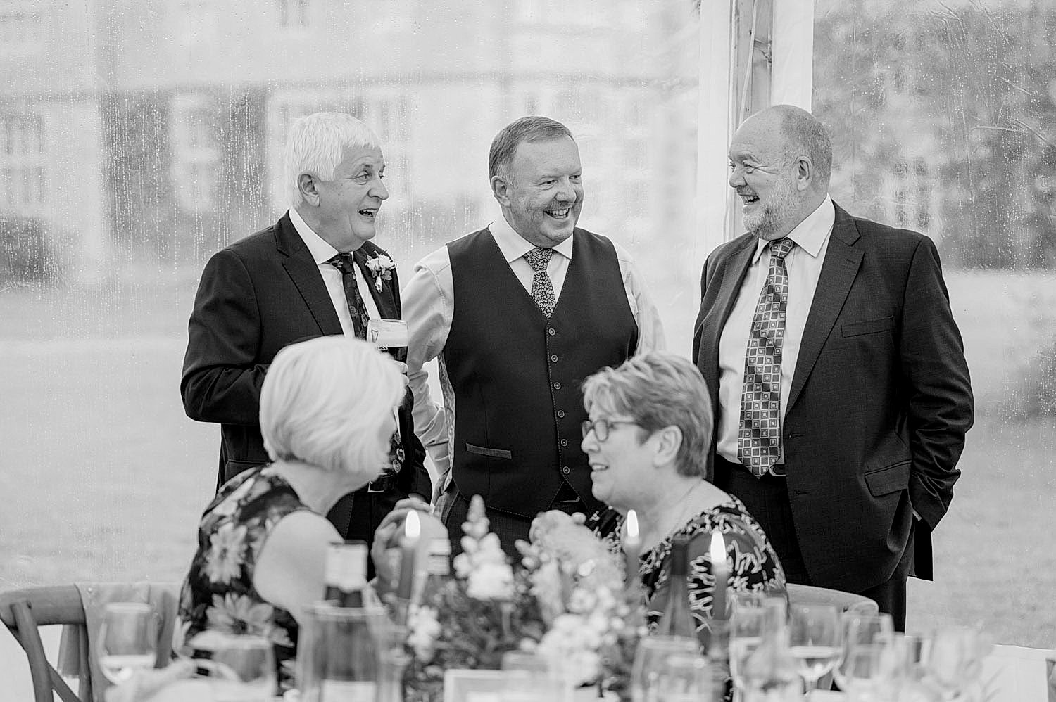 A small group of wedding guests in a little huddle having a chat
