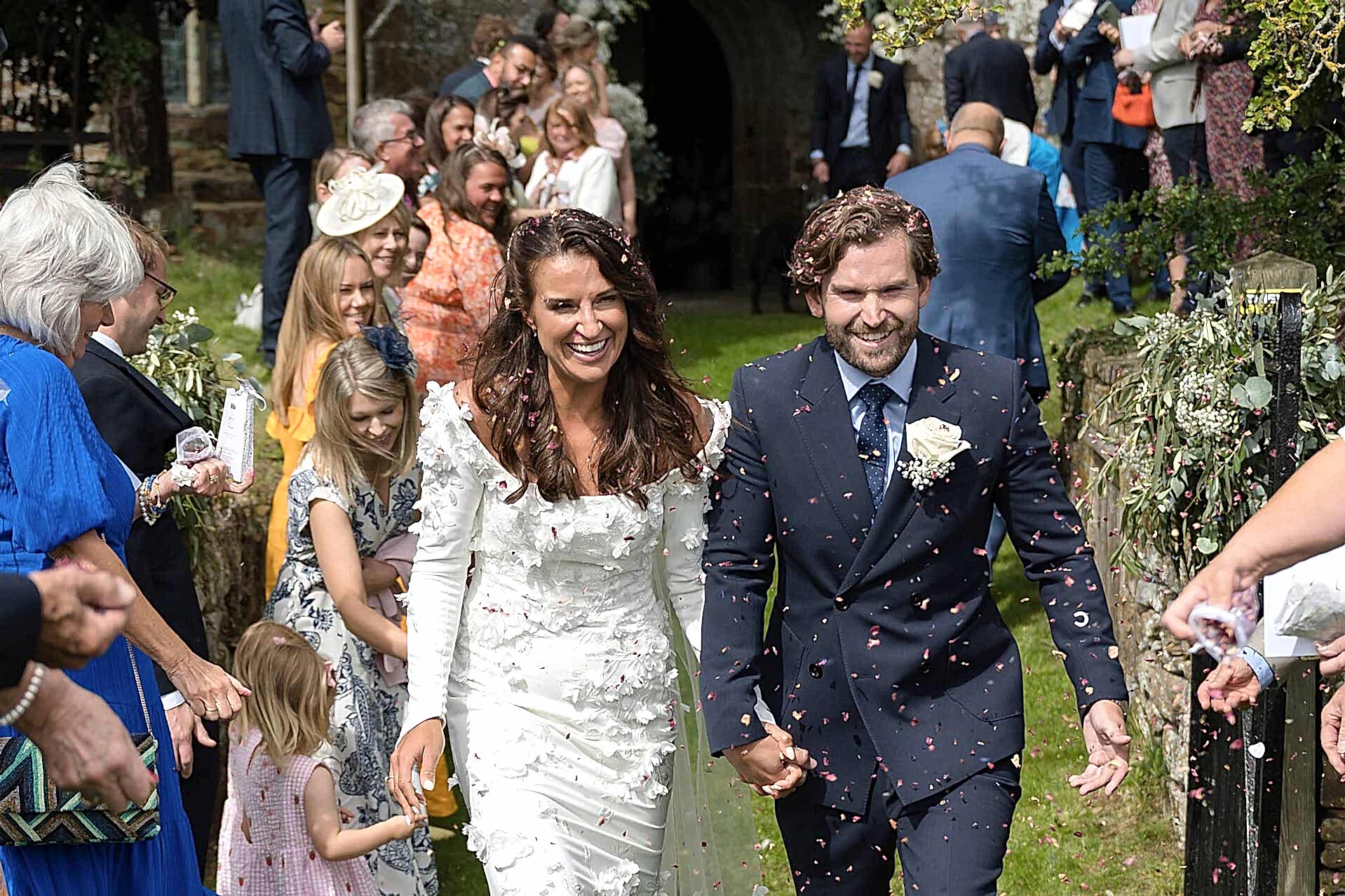 Bride and groom leaving Fawsley church in a cloud of confetti