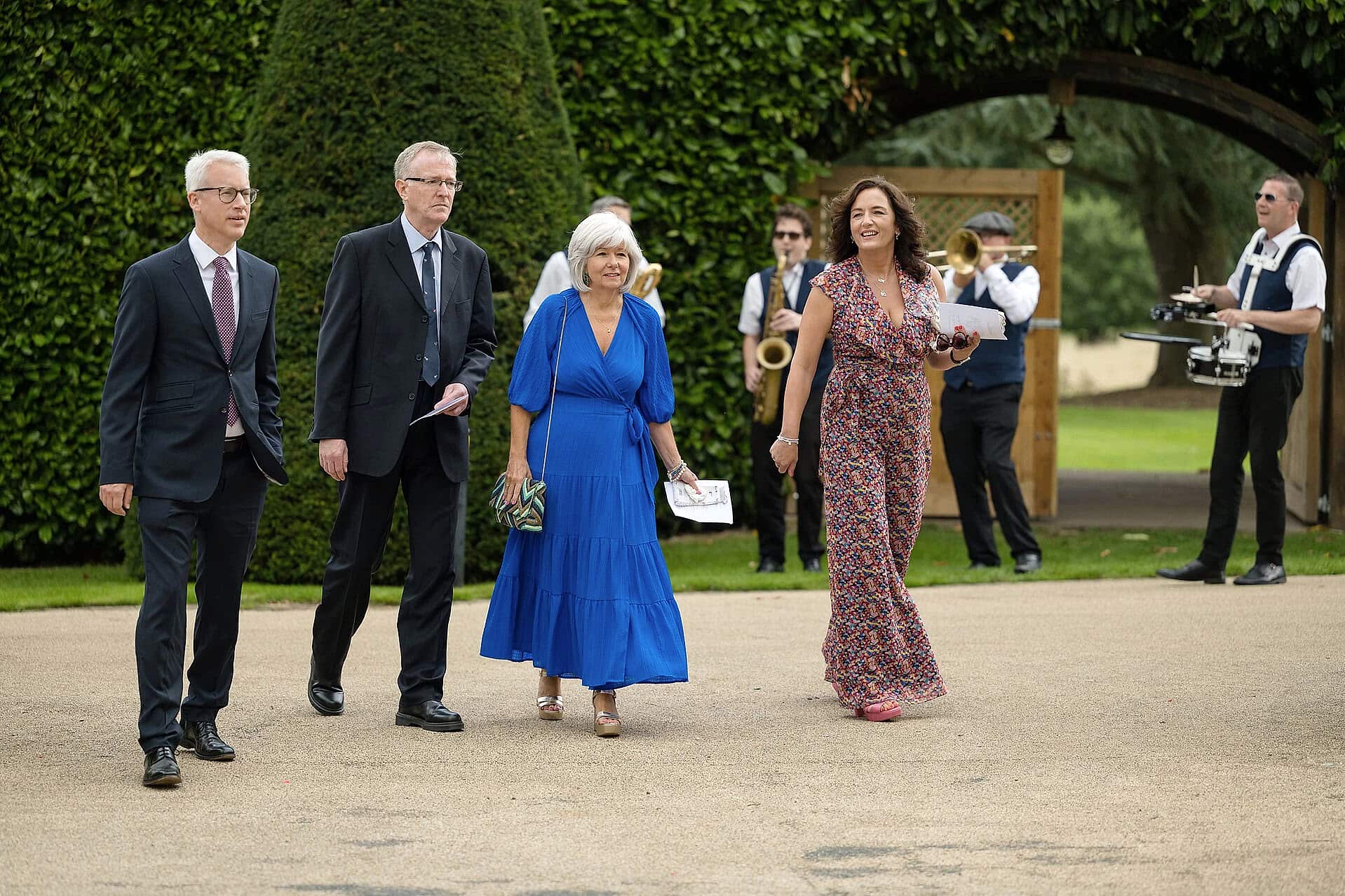 Wedding guests arriving at Fawsley Hall with roaming brass band in background